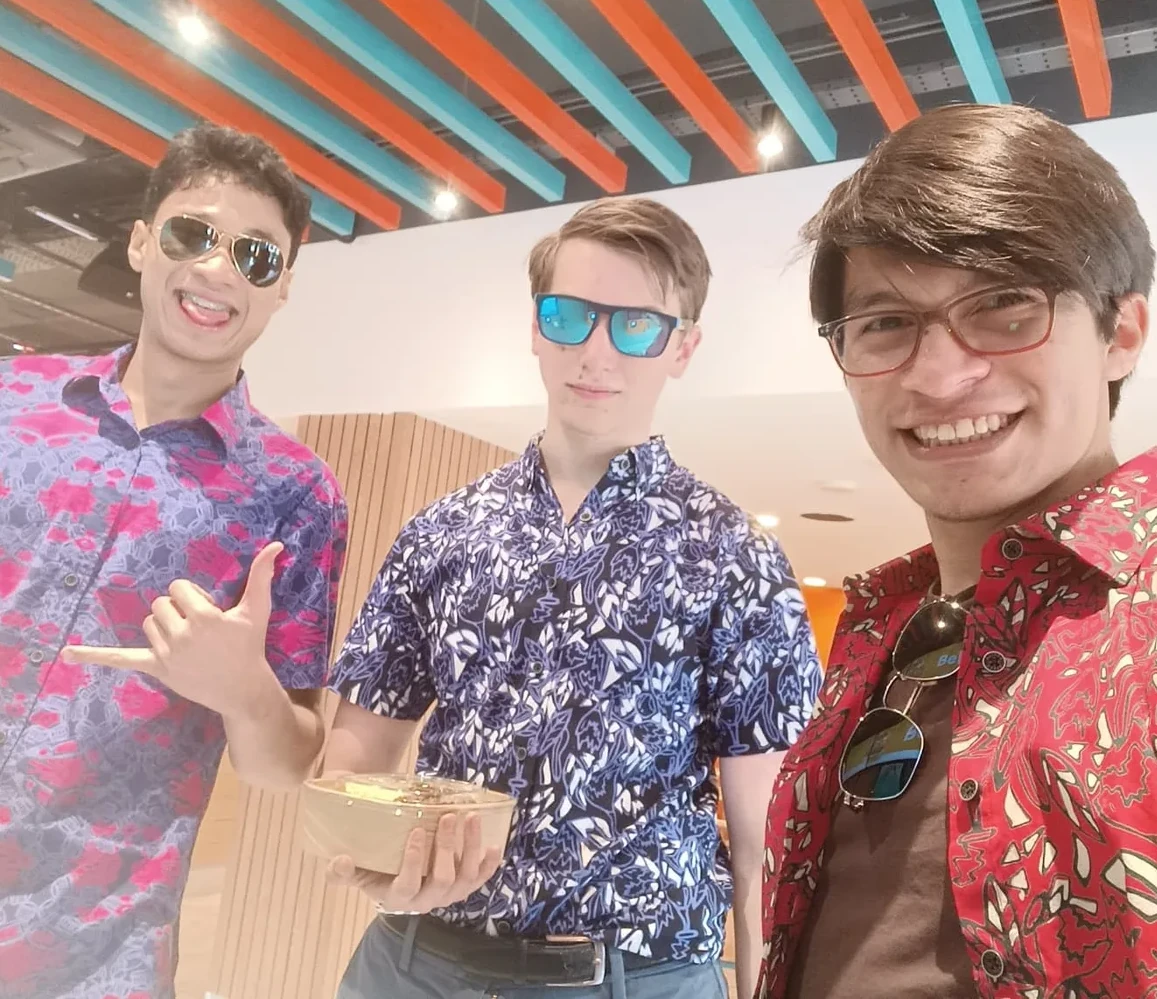 Three friends in colorful shirts posing together indoors